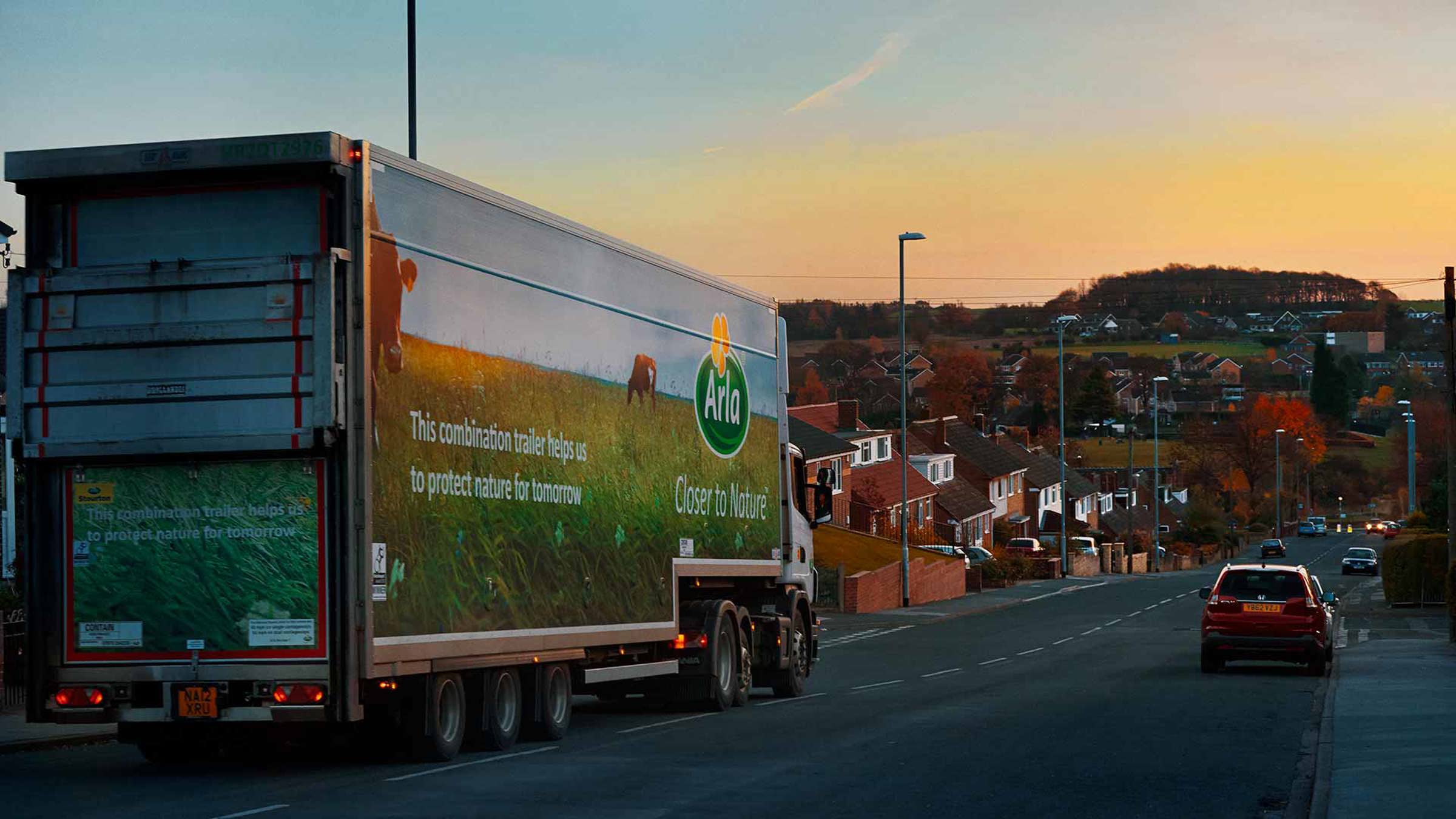 Arla trailer truck driving through a residential area at sunset