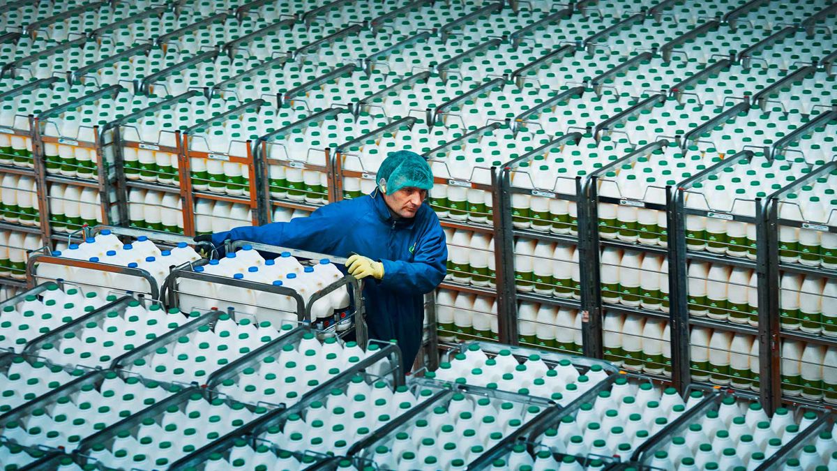 An Arla warehouse worker moving racks of milk