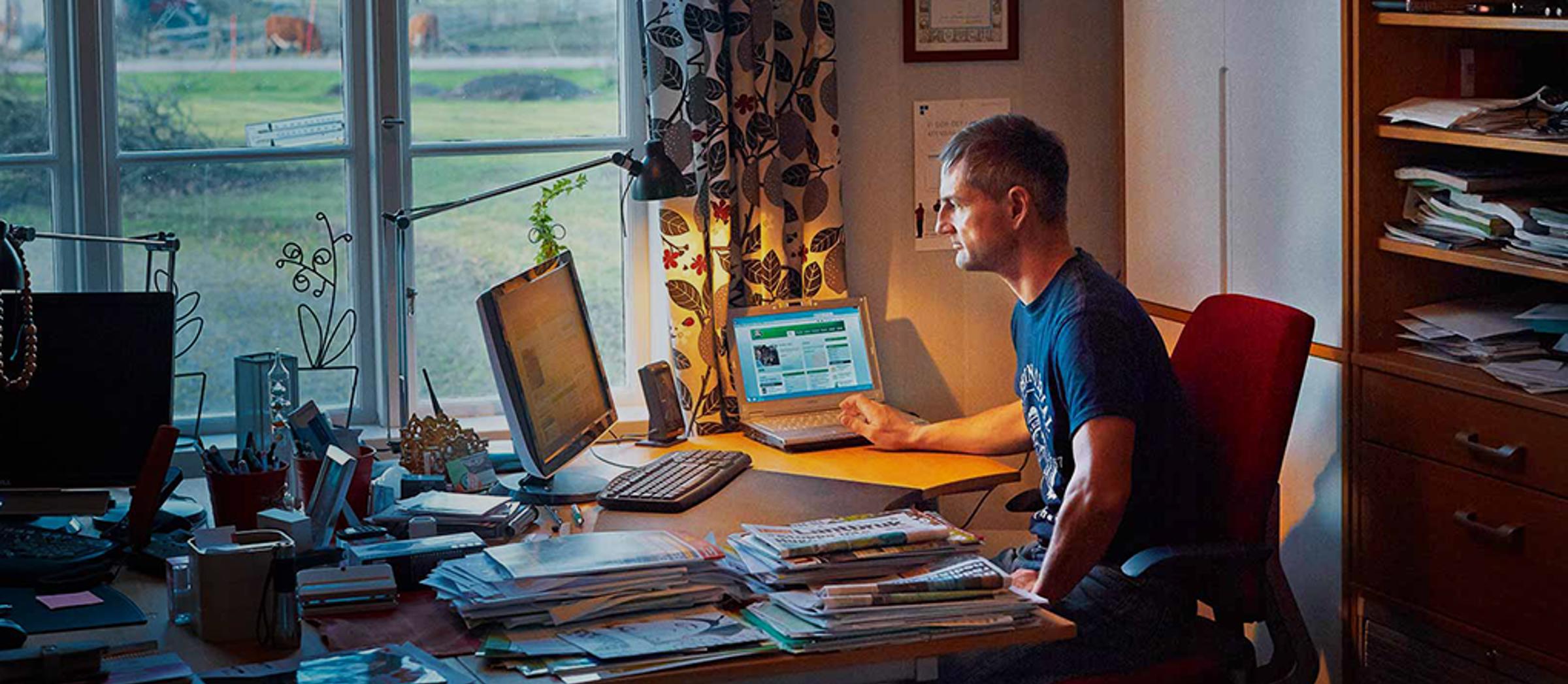 A farmer sat at a desk in his home office