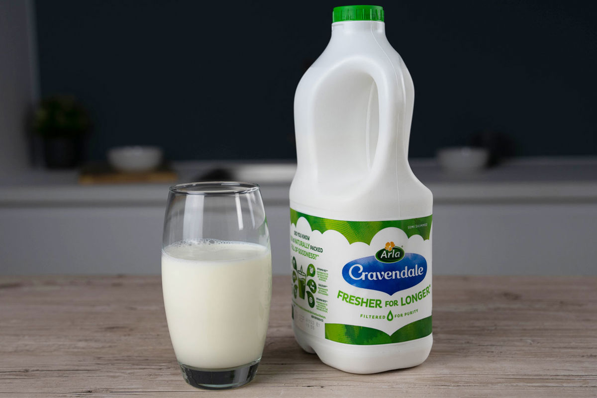 A glass of milk next to a bottle of Arla Cravendale