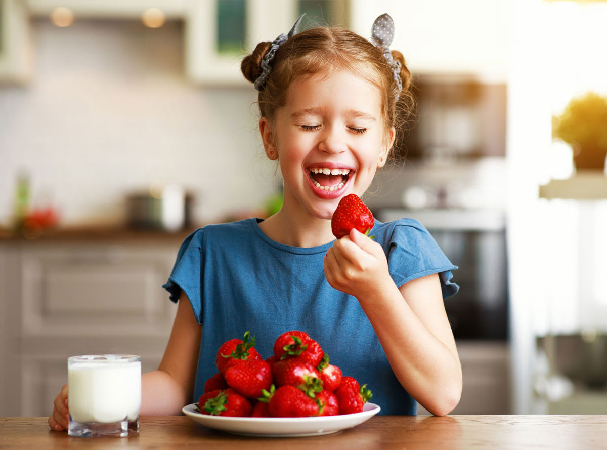 Girl laughing and eating strawberries