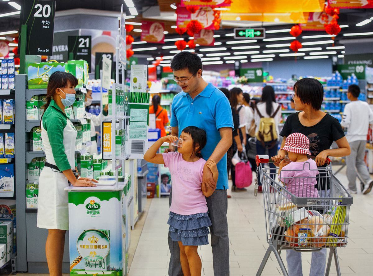 A child sampling Arla milk with her family in a chinese supermarket