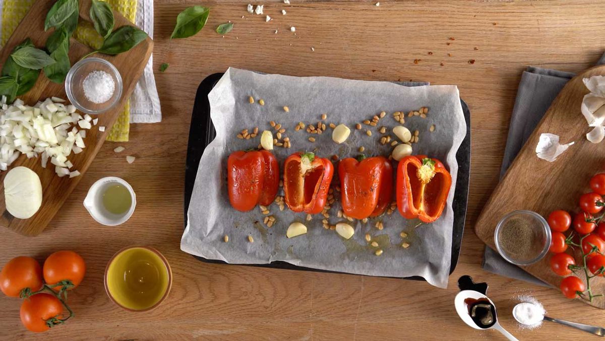 Red peppers, pine nuts and garlic cloves on a baking tray