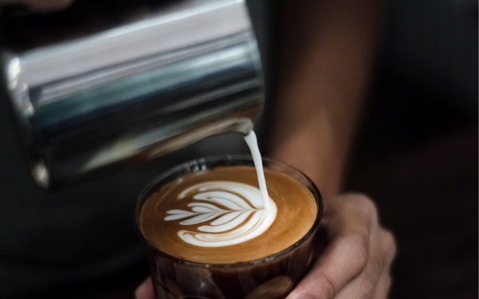 Milk being poured from a jug into a cup of coffee