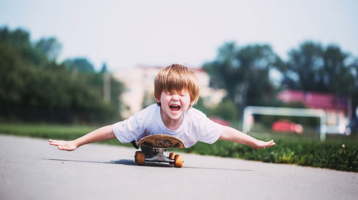 A boy lying down on a moving skateboard