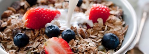 Milk being added to a bowl of oats with berries