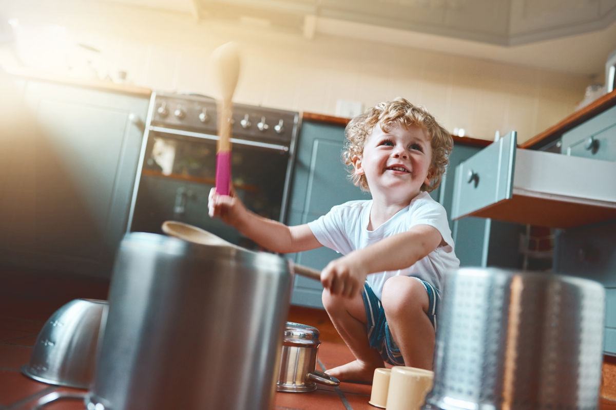 A child banging on pots and pans in a kitchen