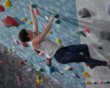 Woman in action shot climbing an indoor practice wall