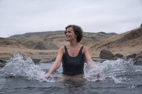 Woman splashing water in a lake and smiling away from the camera