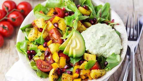 Bowl of fresh salad, tomatoes, peppers, pomegranate seeds with a side of Arla Sykr Guacamole
