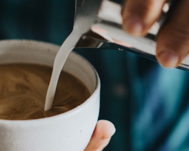 Milk being poured into a cup of espresso