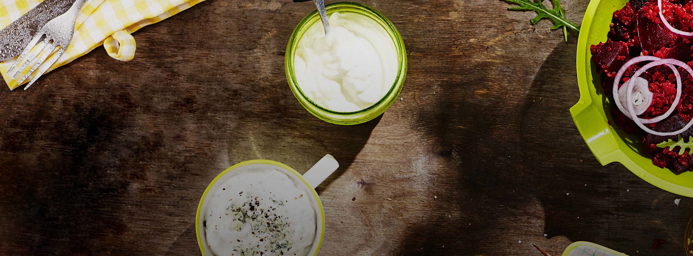 Jars of yogurt and a bowl of beetroot and quinoa salad on a wooden surface