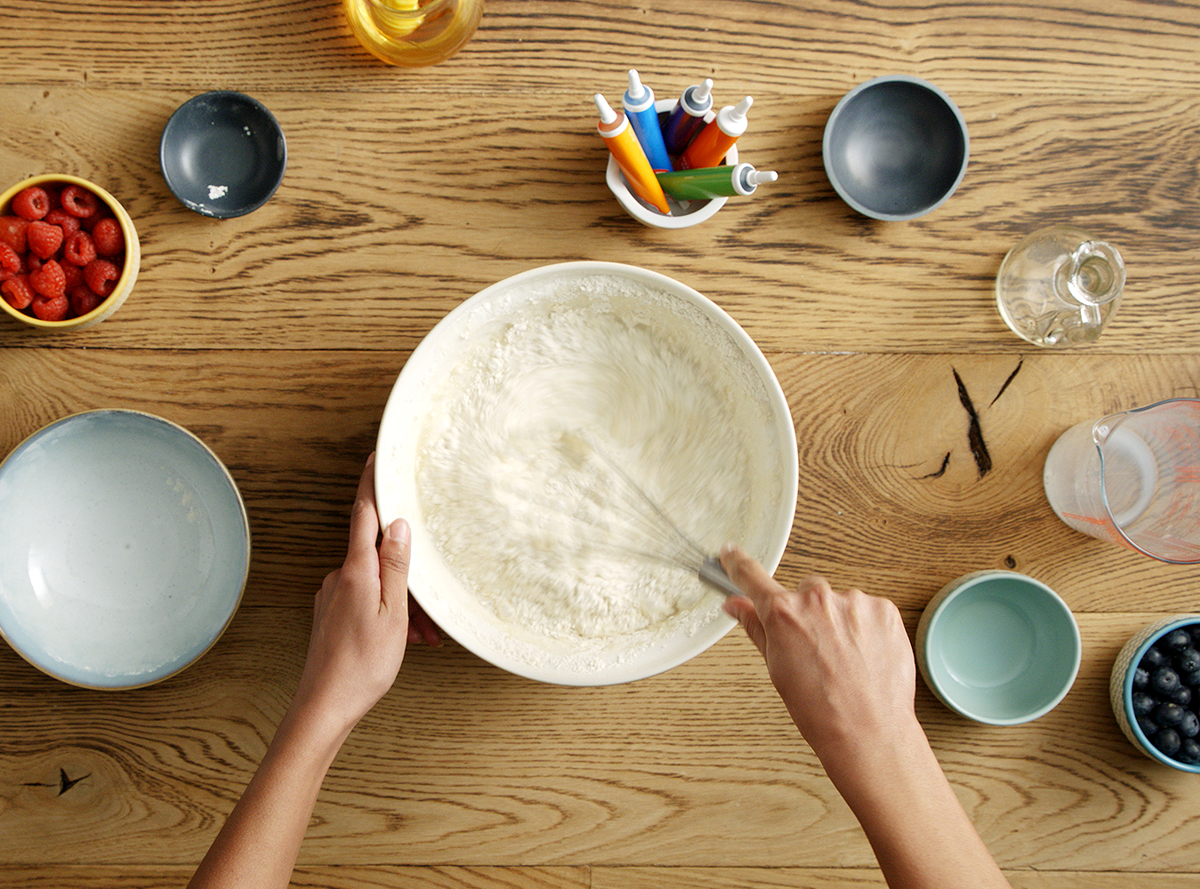 a pair of hands whisking batter in a bowl