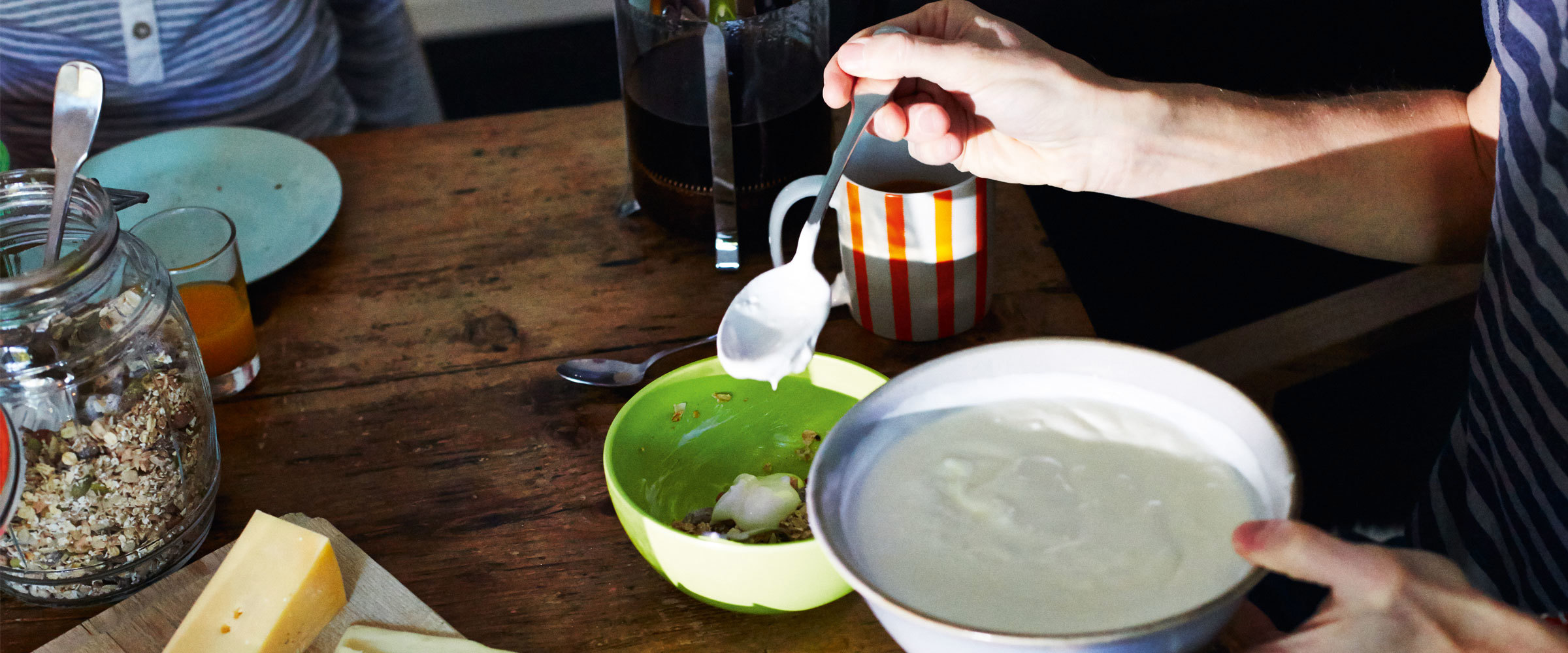 A person mixing yoghurt with grains in a bowl