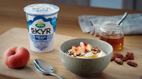 Pot of Arla Creamy Skyr with a bowl of Skyr and fruit.