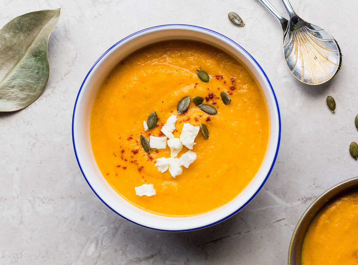 A bowl of pumpkin soup topped with seeds