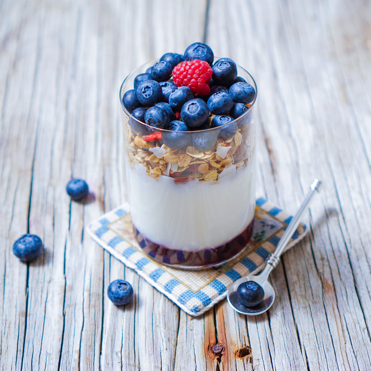 A glass of berries and yogurt on a wooden surface