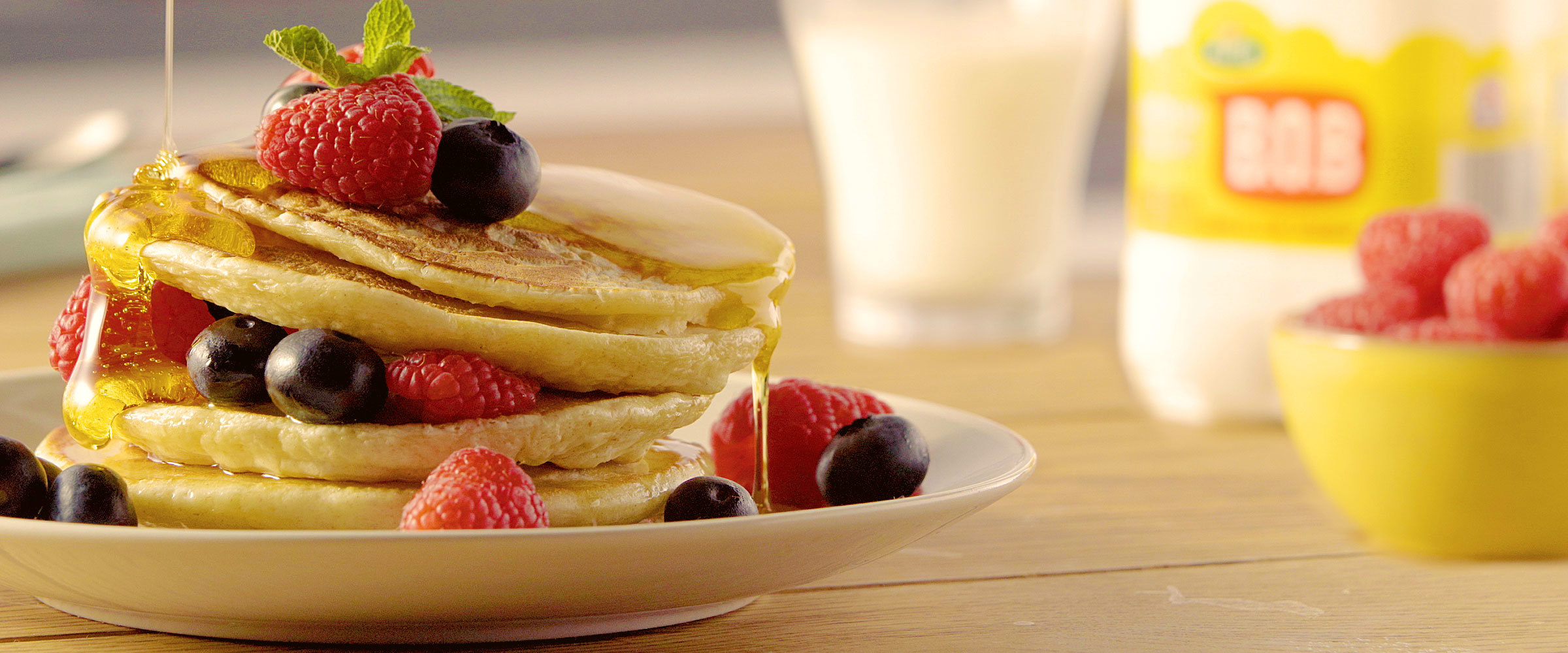 A stack of pancakes covered in honey and berries