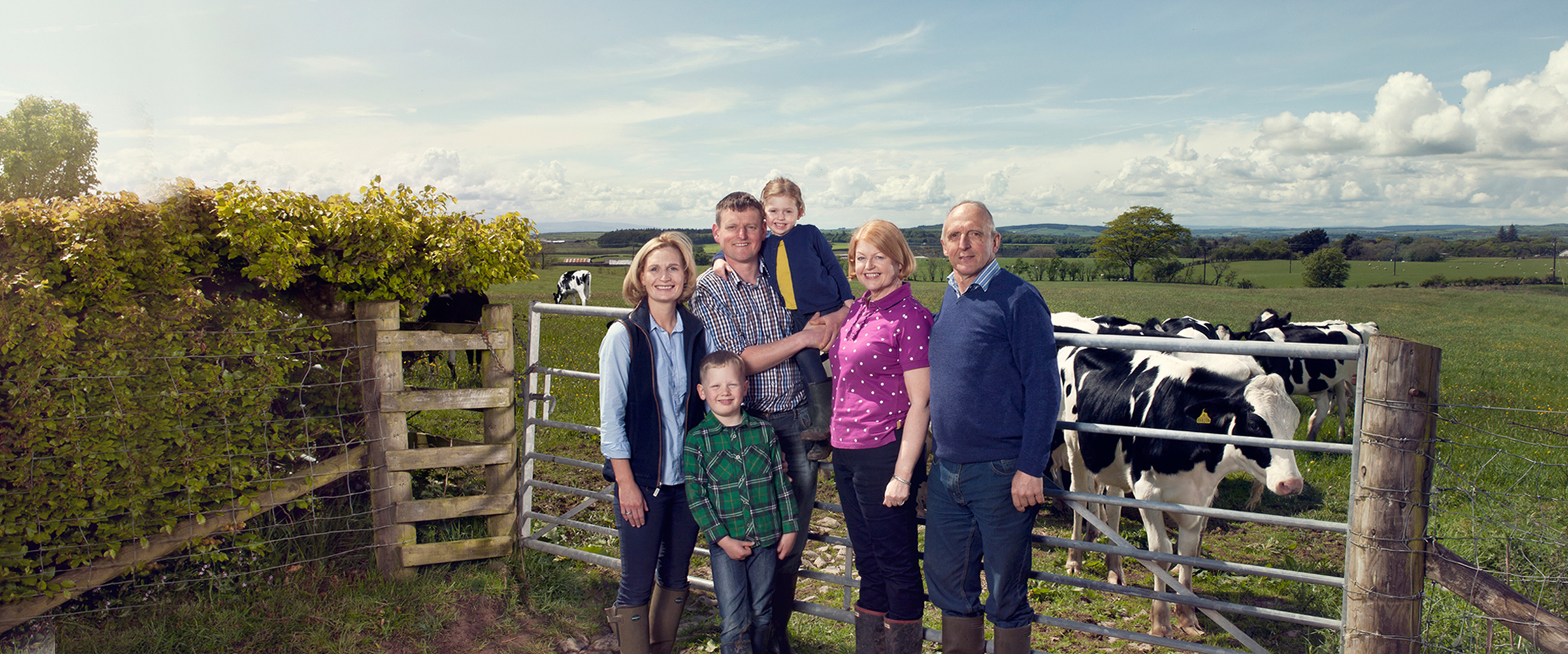 Portrait of farmers and children in front of cows in a field