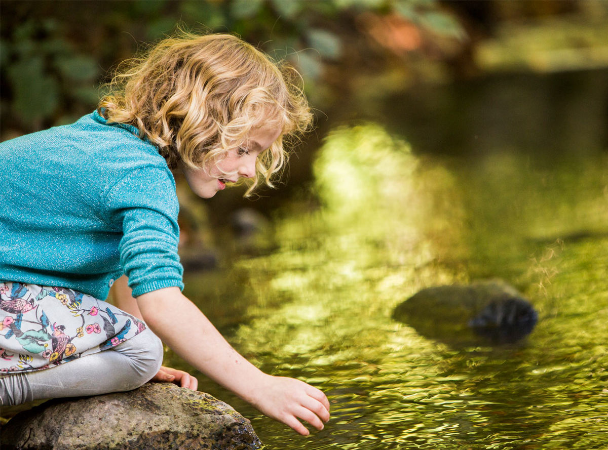 Girl reaching into a body of water