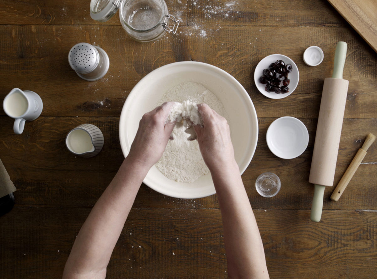 A pair of hands working butter into a bowl of flour