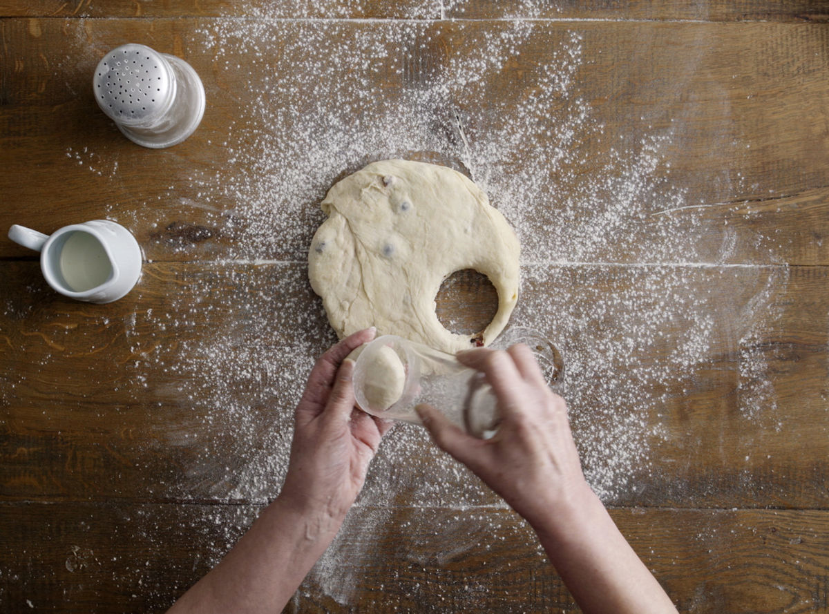 a pair of hands cutting out circles from dough with a tumbler