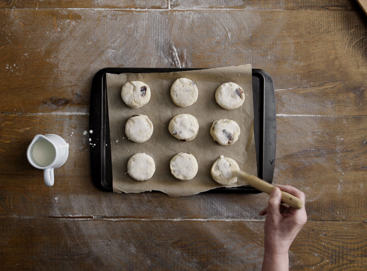 Uncooked scones being glazed on a tray