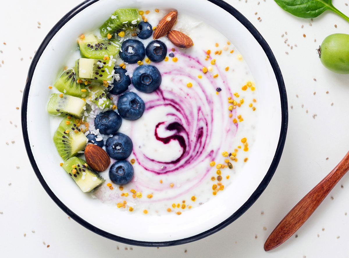 A bowl of yogurt topped with blueberries, kiwi fruit and almonds