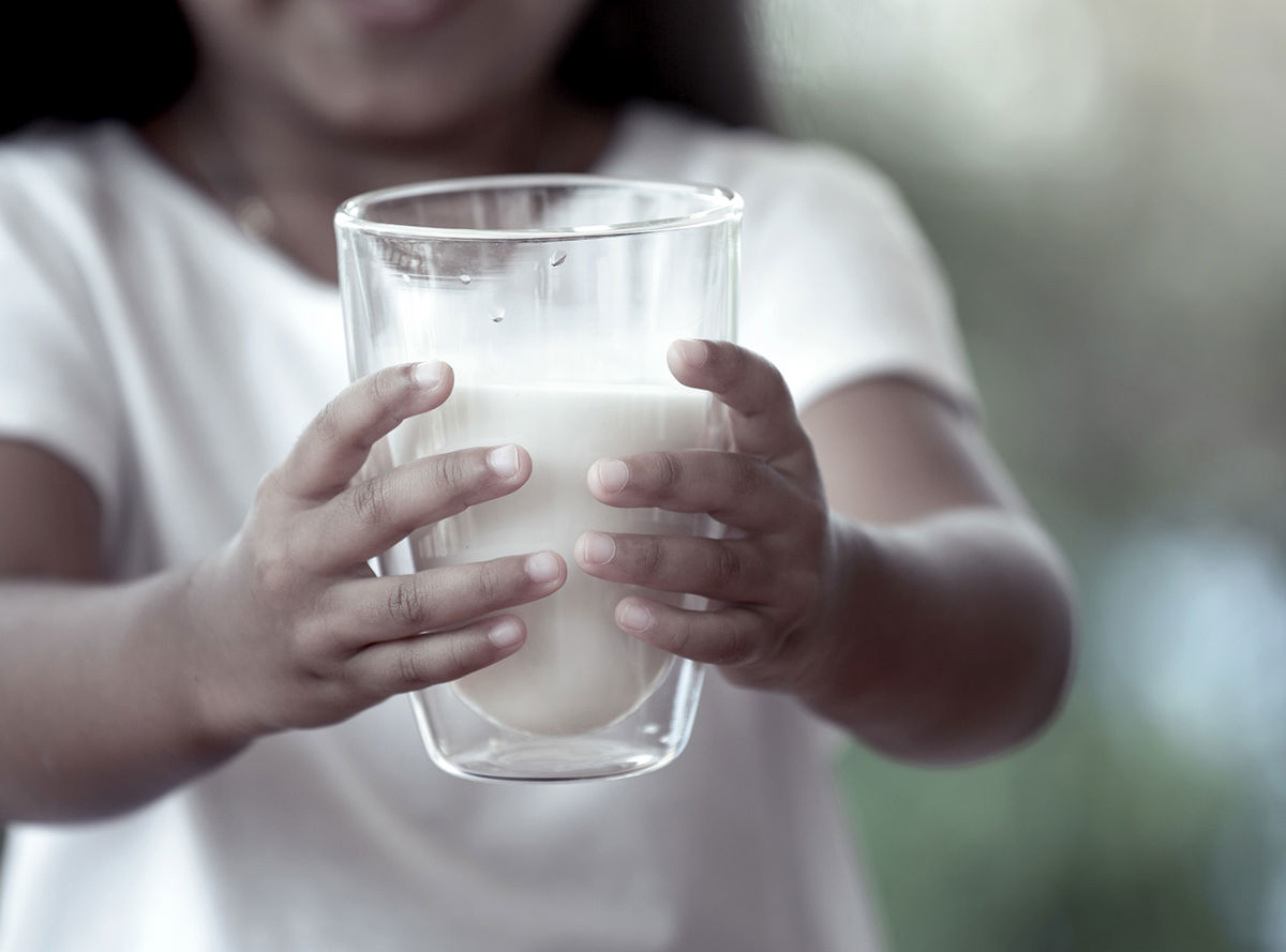 A girl holding out a glass of milk