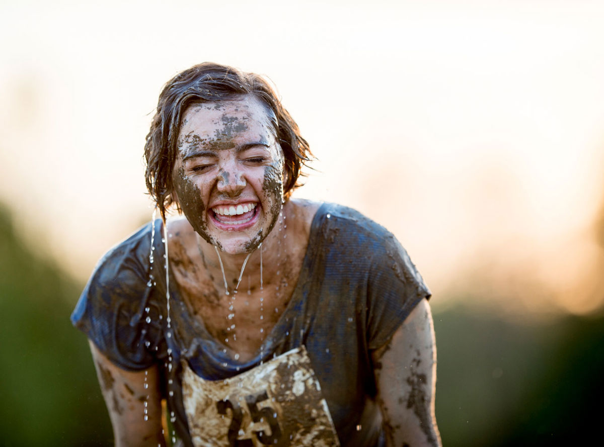 Female runner covered in mud and water smiling