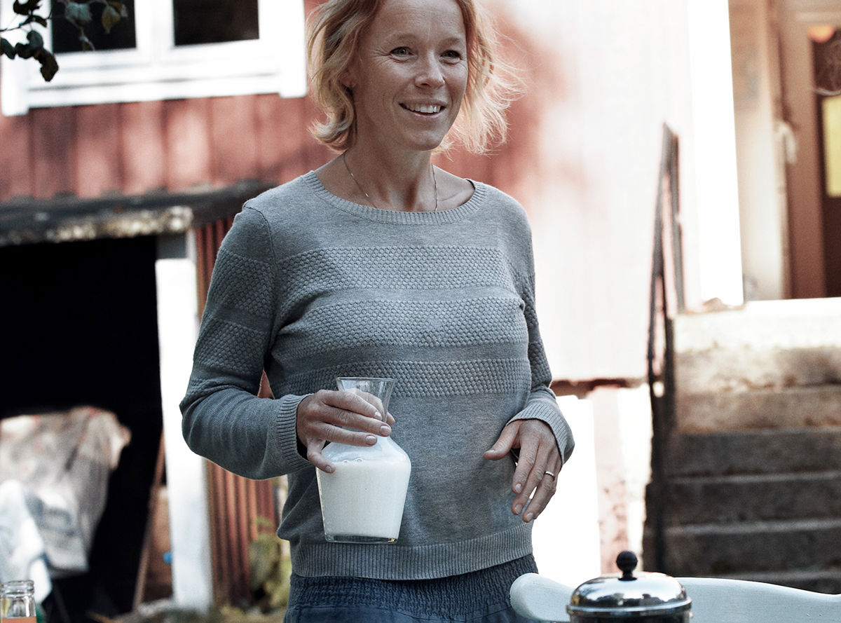 A woman holding a jug of milk outdoors