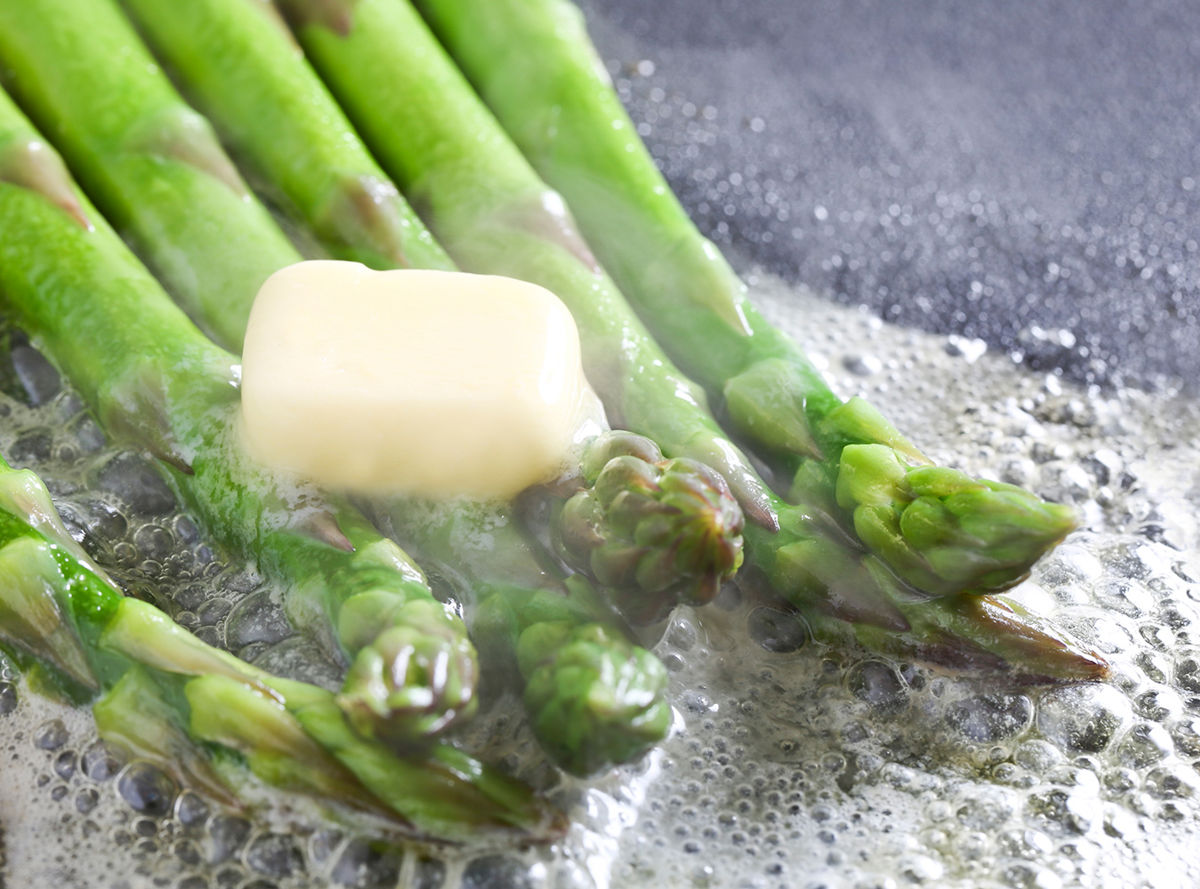Butter melting onto cooking asparagus