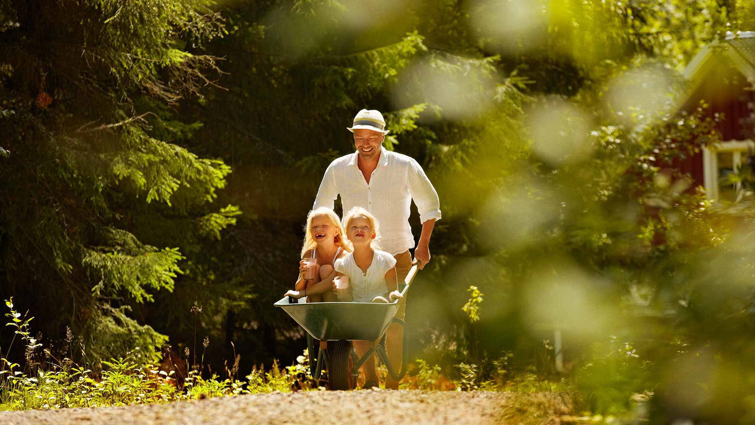 A father wheeling two girls in a wheelbarrow