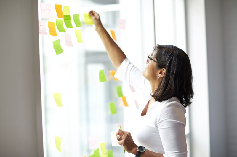 A woman placing a post it note on a window