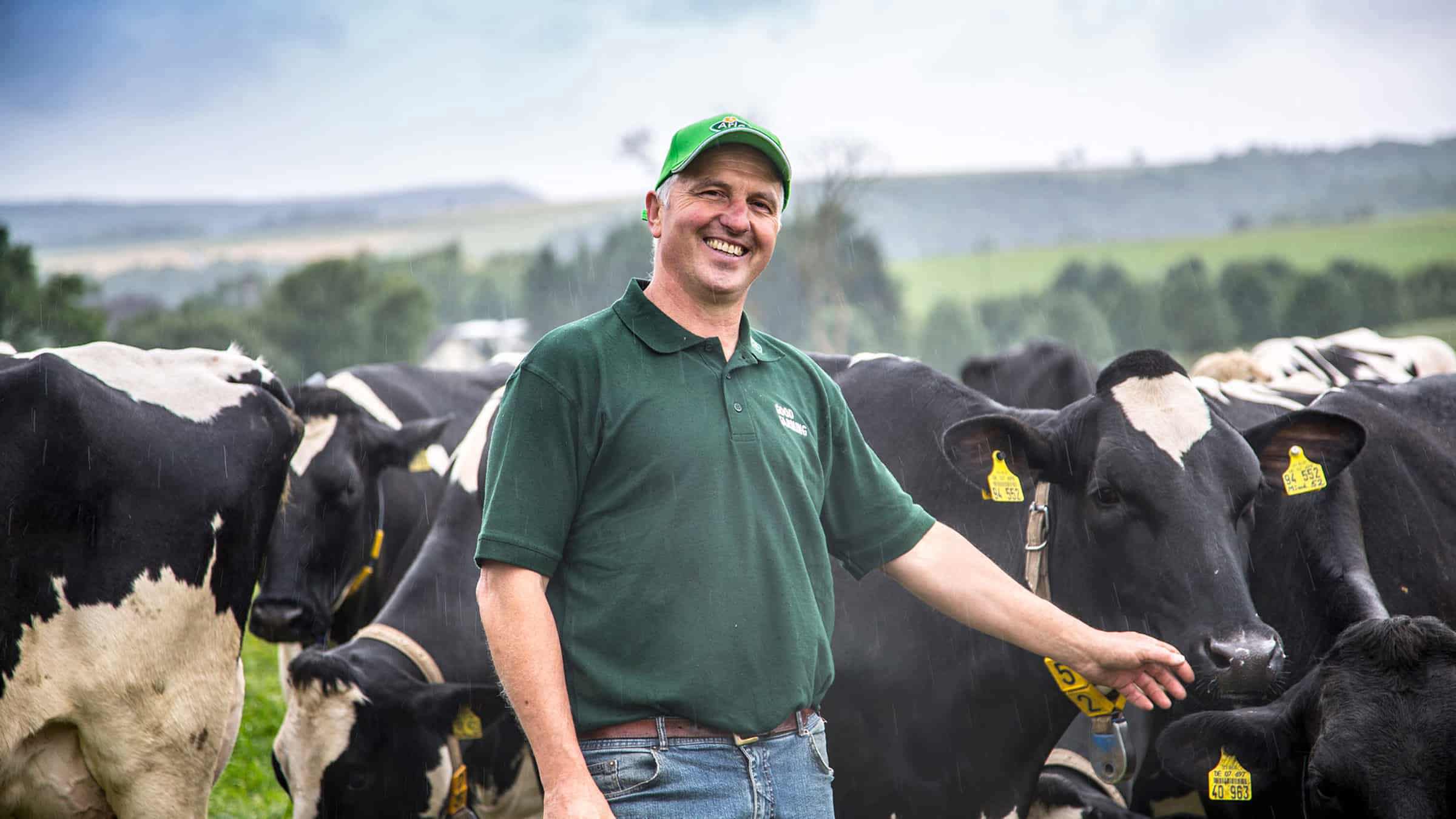 Farmer smiling in a field with cows