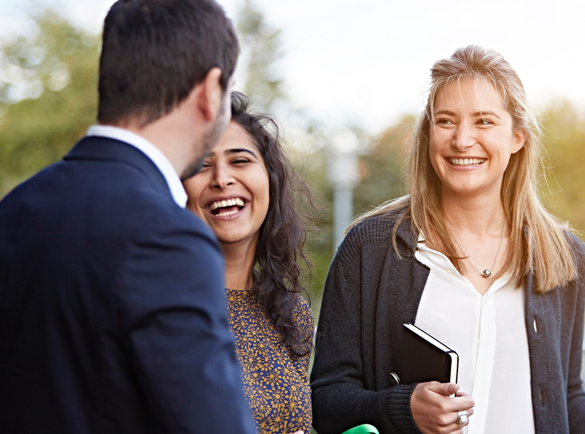 Two women and one man laughing in conversation