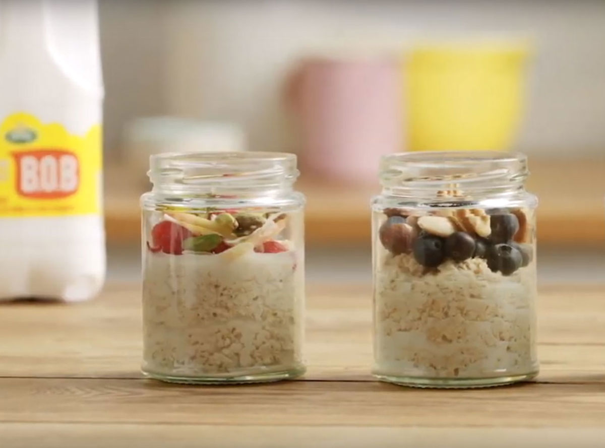 Two jars of overnight oats with nuts and berry toppings