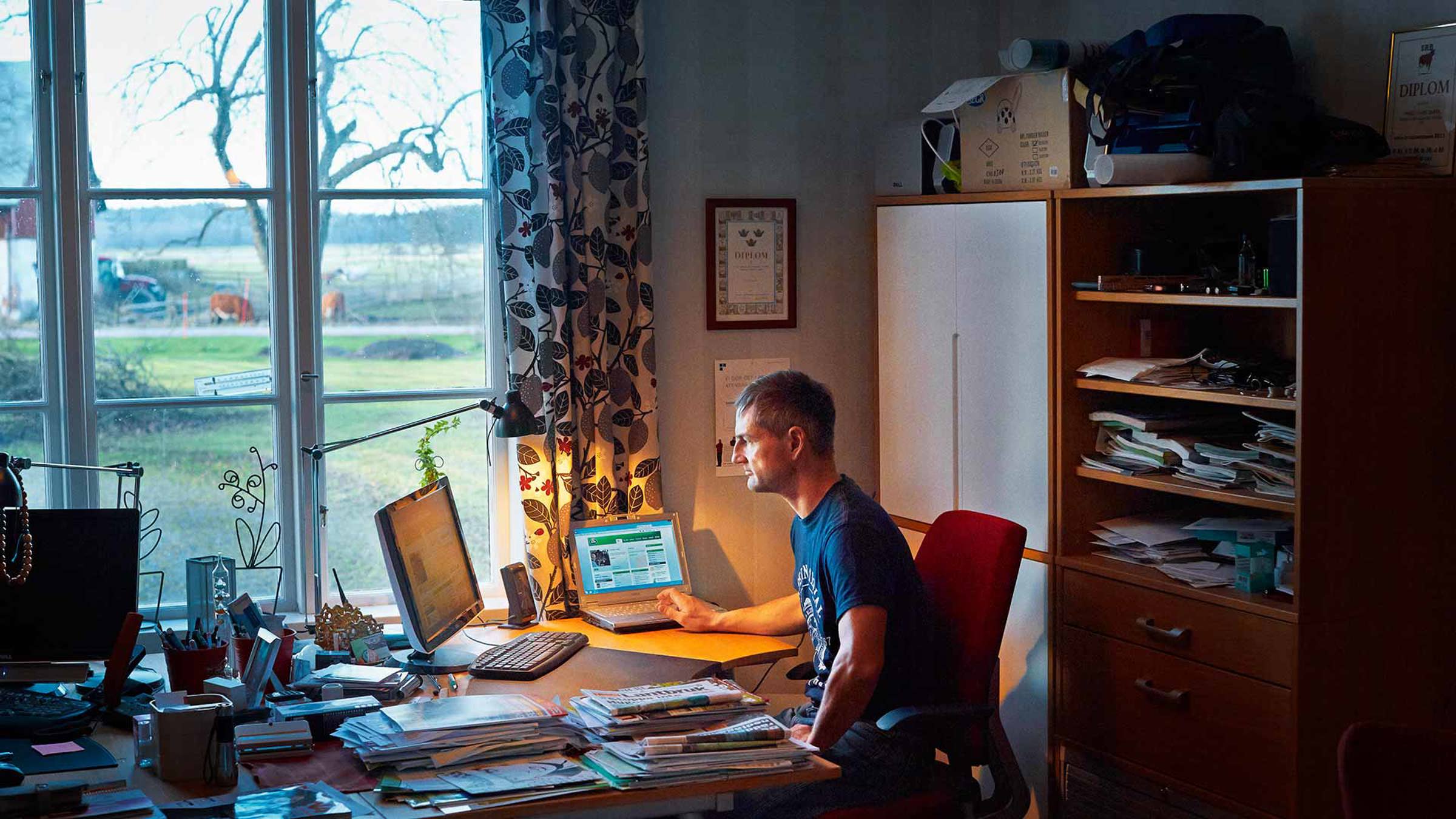 Farmer using a computer sat at a desk in his home office