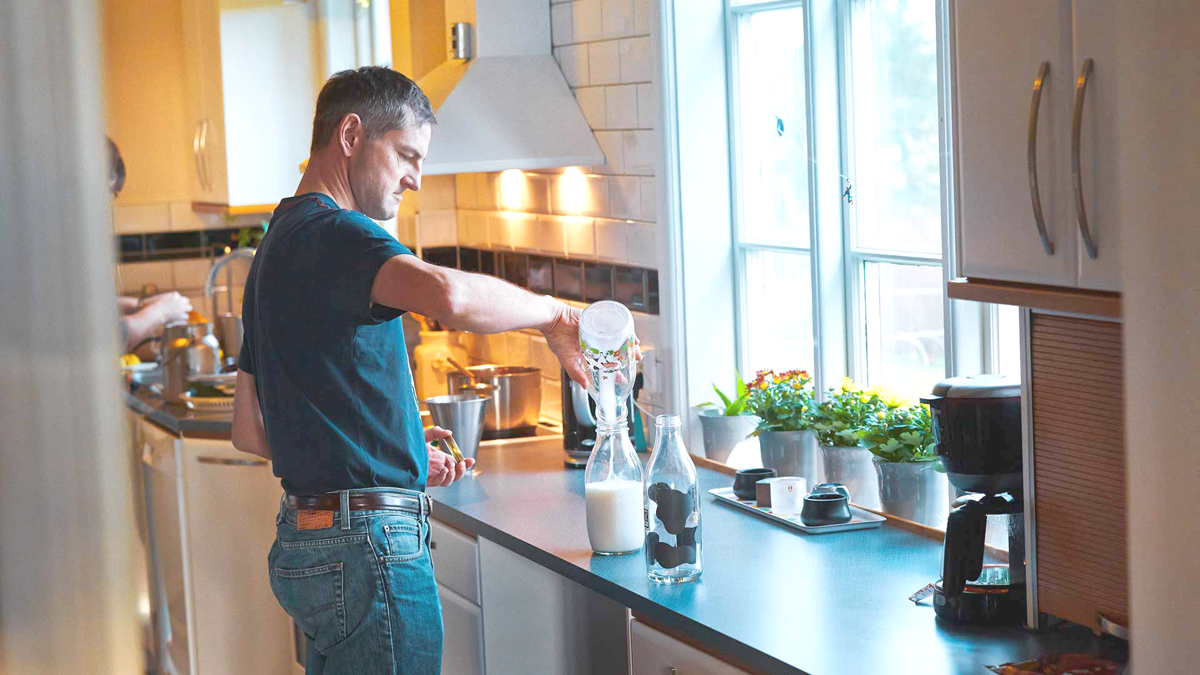 Man decanting a milk into a jar in a kitchen
