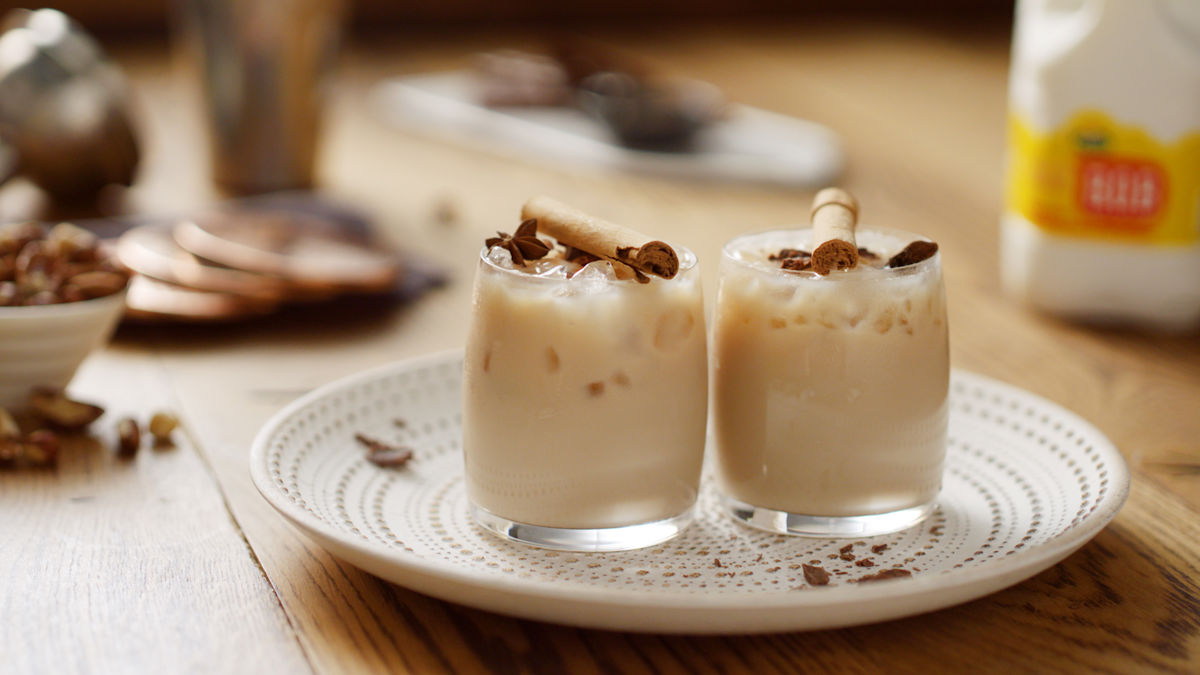 Two glasses of white russian topped with cinnamon sticks