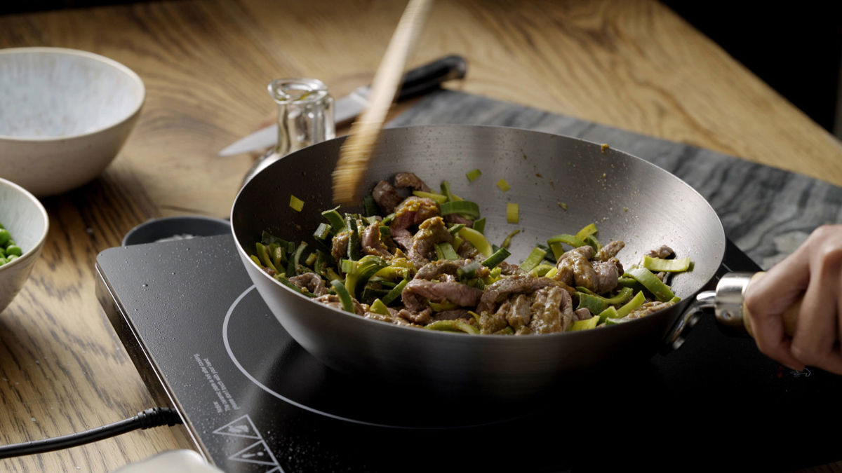 Beef and vegetables being stirred in a wok