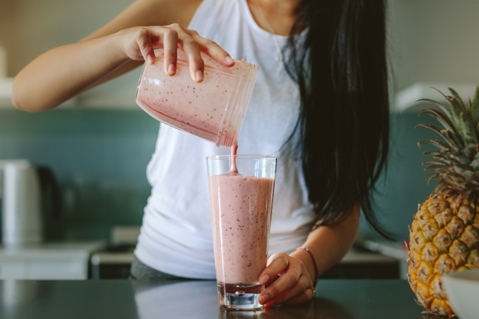 A woman pouring smoothie into a glass