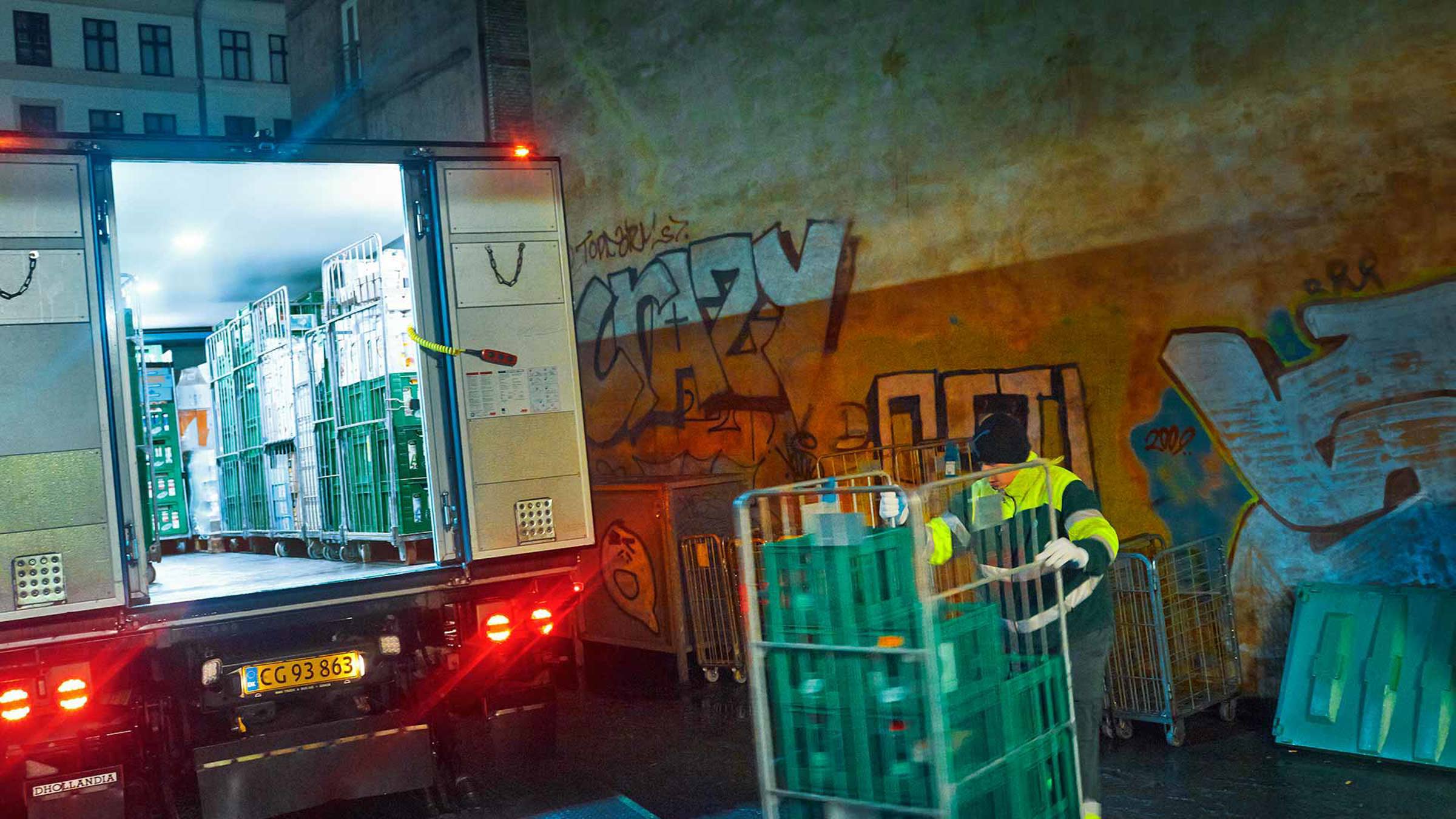 A worker loading trolleys into a truck at night
