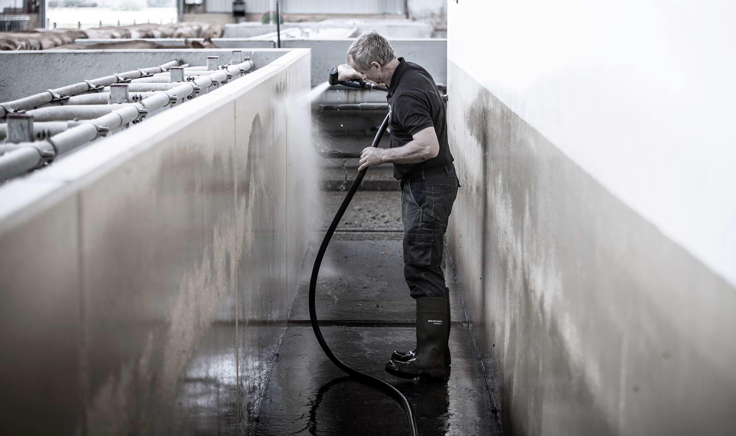 A farmer hosing down a wall